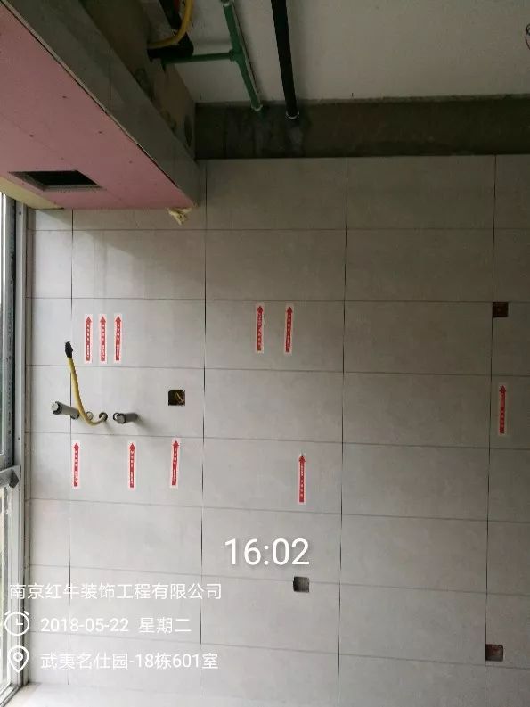 南京武夷名仕園124平米簡美風（fēng）格裝修（xiū）  享受家帶來的溫（wēn）度30五月份_牆磚鋪貼完成（chéng）後，紅牛裝飾的工人會用（yòng）專用（yòng）護角條對瓷磚角保護，用標貼標出水（shuǐ）管、線管走向示意。